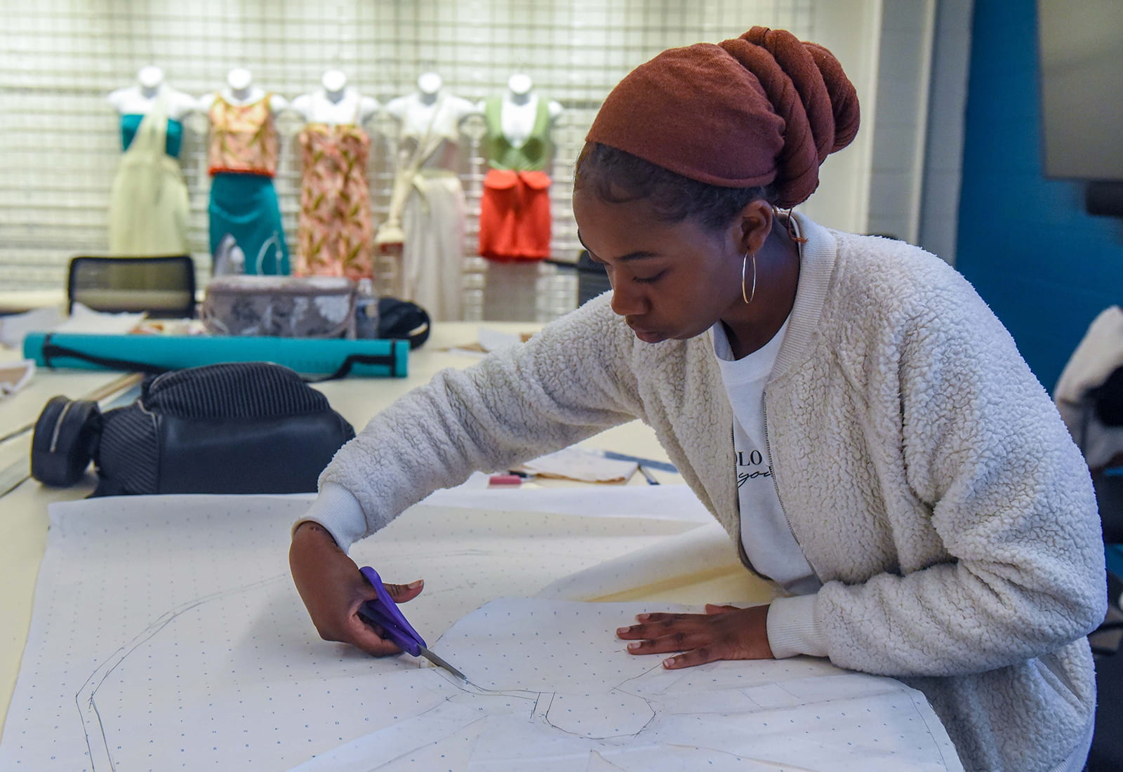 A student cutting out a clothing pattern outline