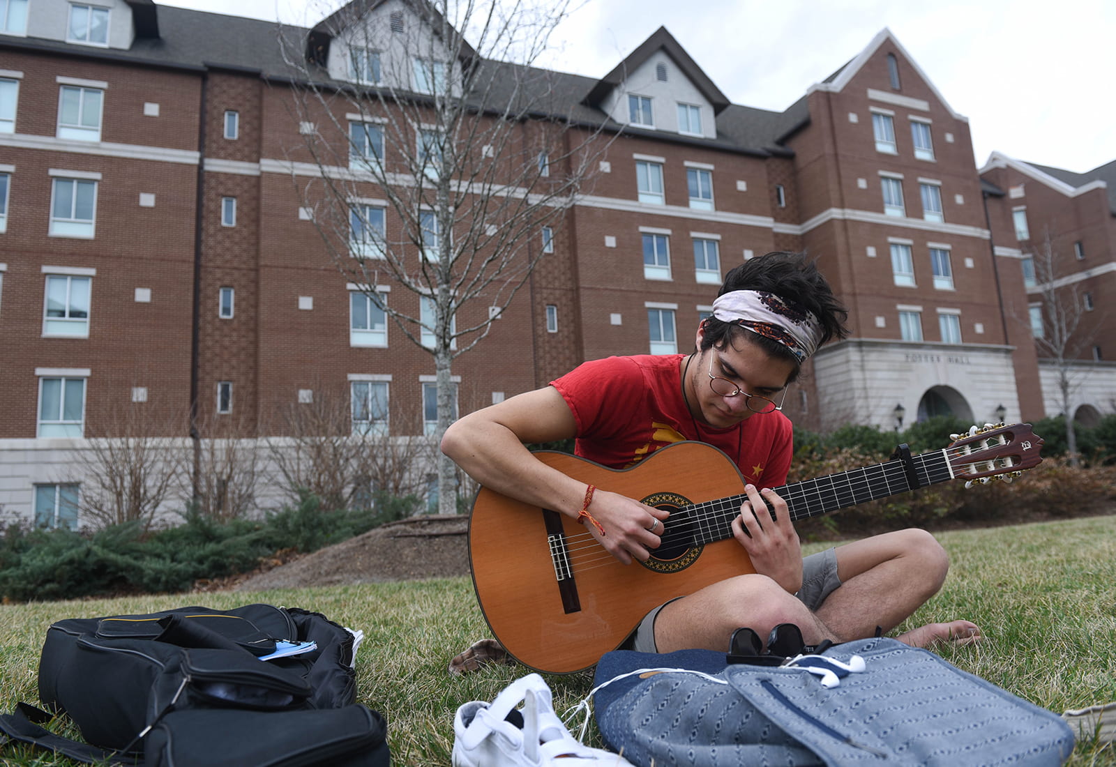 A student playing guitar on the lawn of Belmont University
